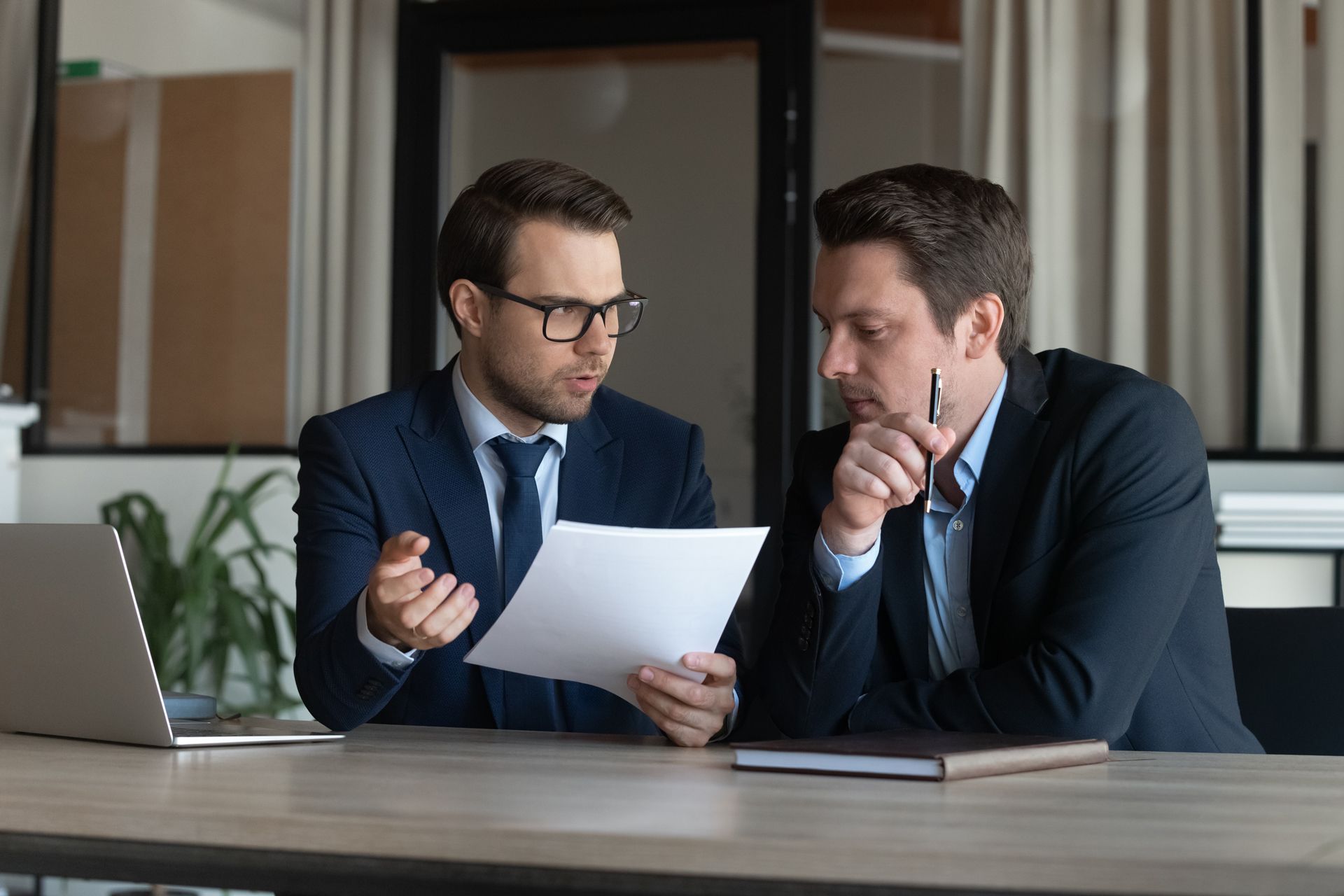 Two Men Are Sitting at a Table Looking at a Piece of Paper