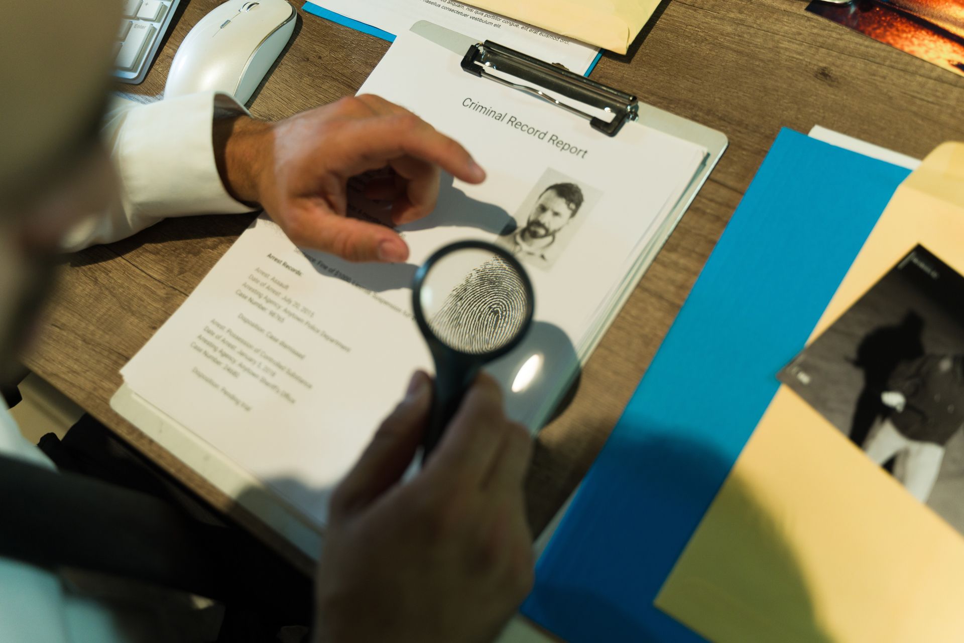 A man is looking at a fingerprint on a clipboard with a magnifying glass.