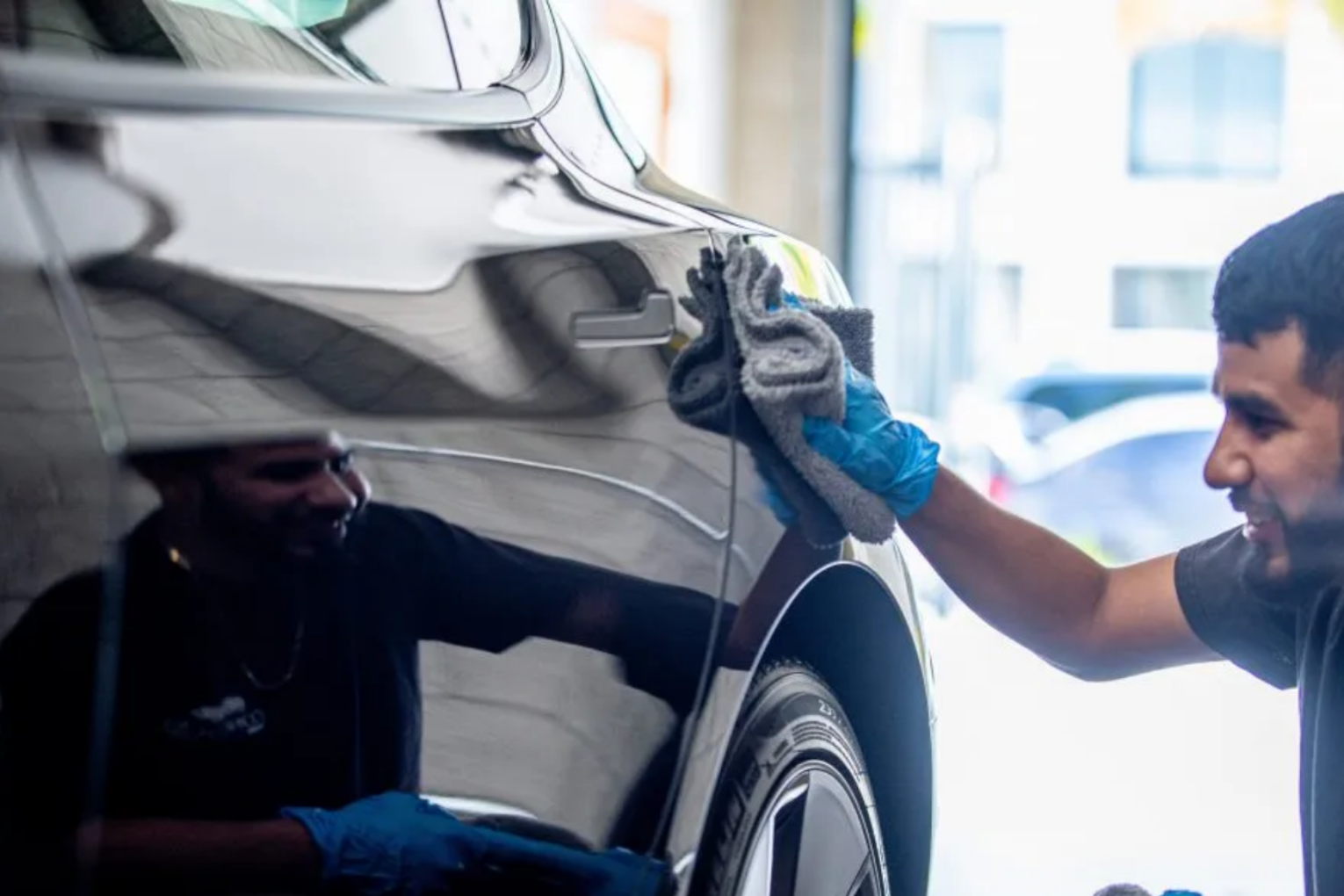 A person using a pressure washer to clean the siding of a house.
