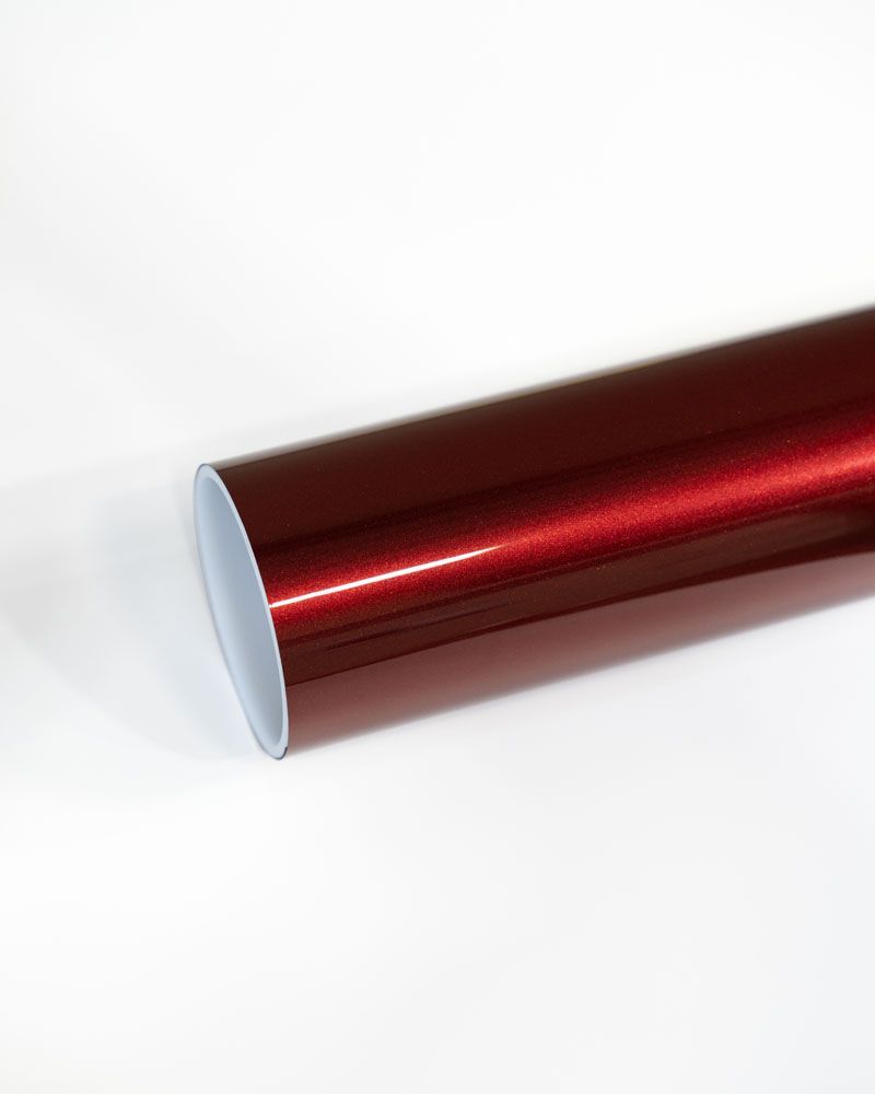 A roll of red metallic vinyl wrap is sitting on a white surface.