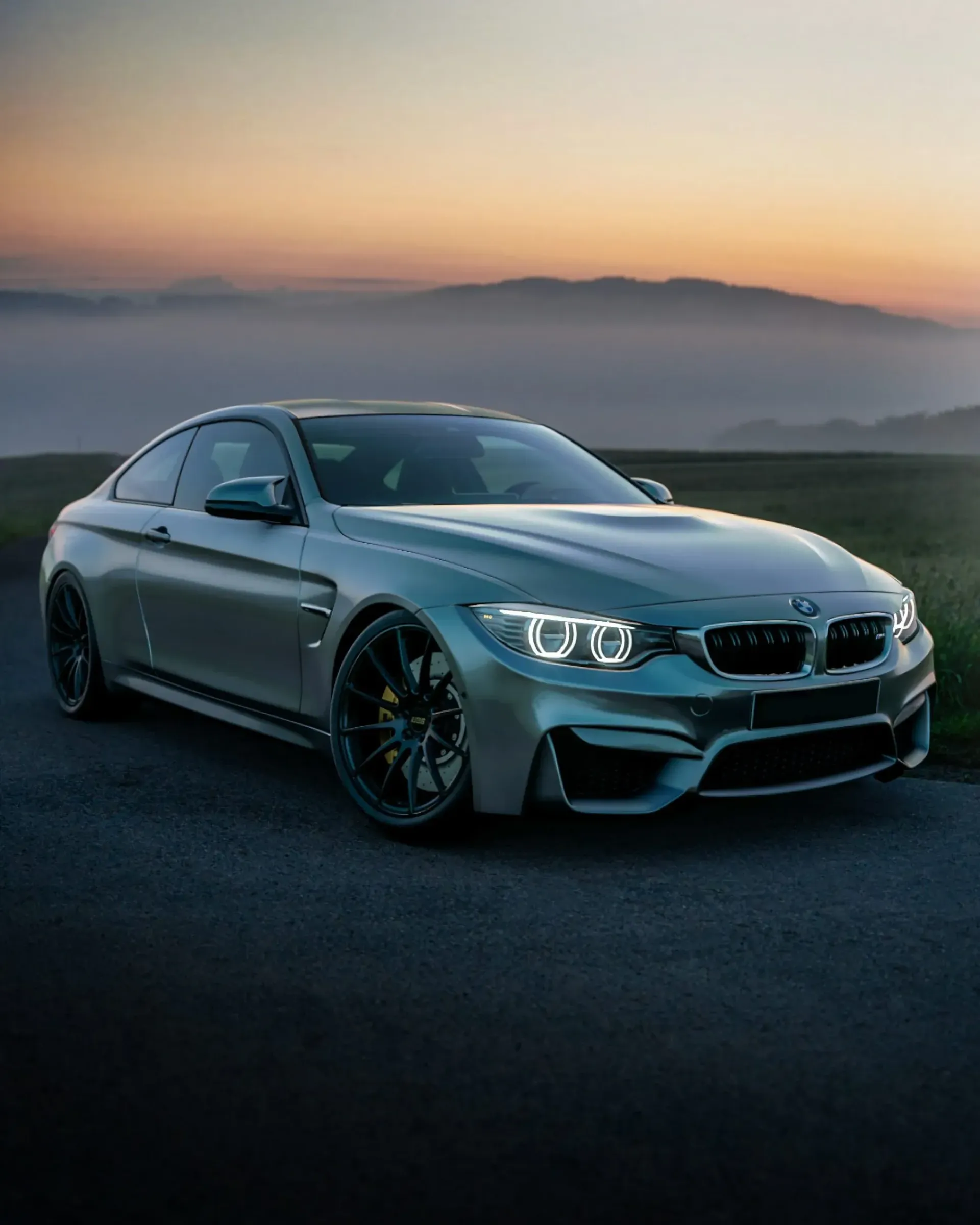 A silver bmw m4 is parked on the side of a road.