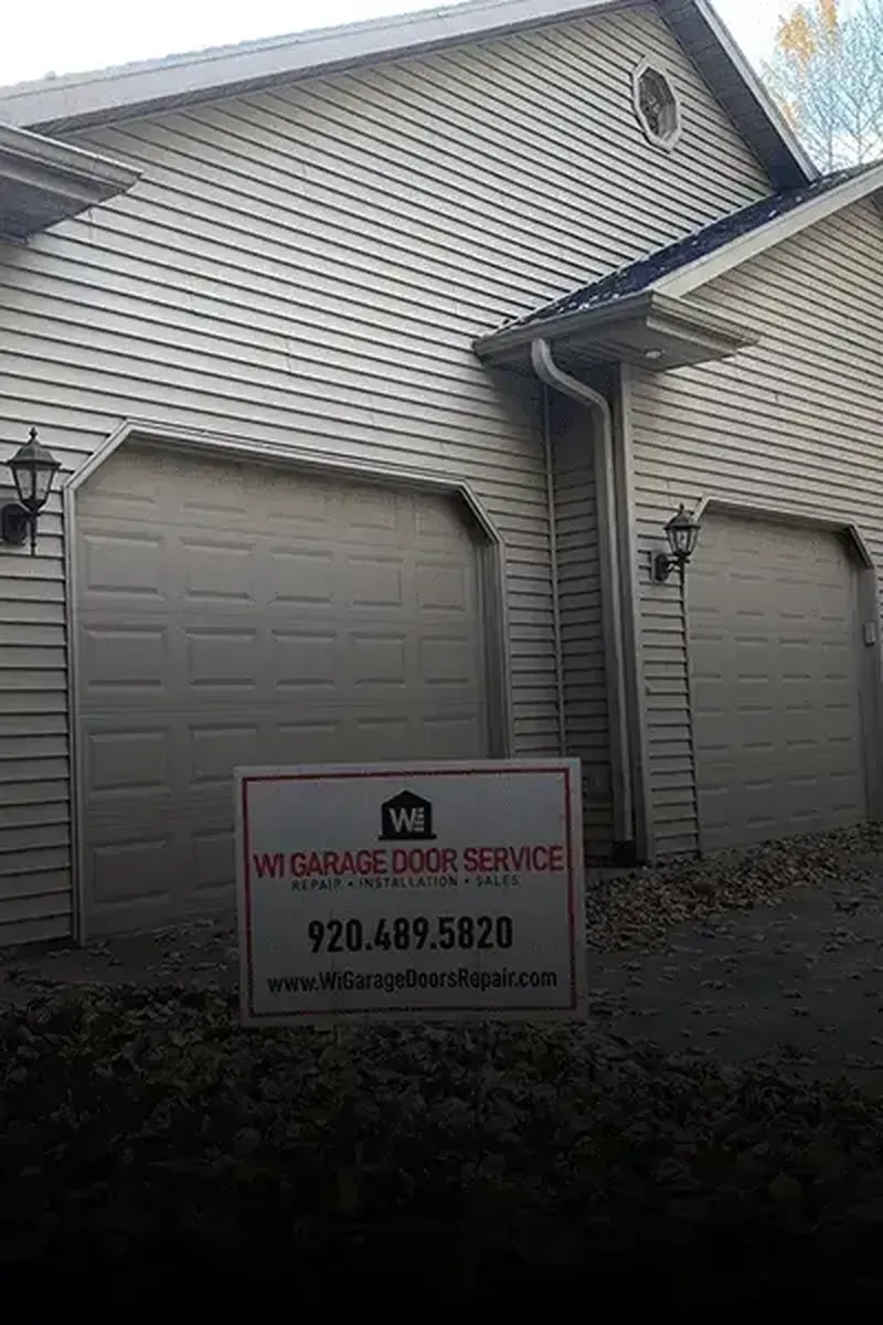 A beige house with two garage doors and a Wisconsin Garage Door Service sign in the foreground.