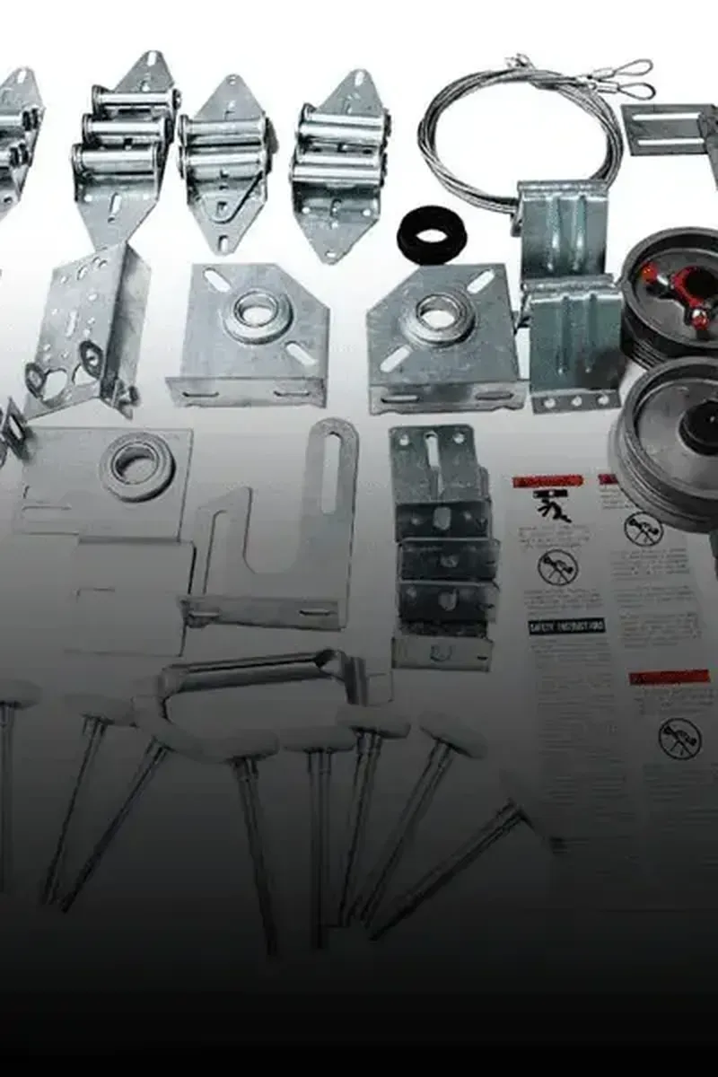 A collection of metal garage door replacement parts, including hinges, rollers, cables, pulleys, and mounting brackets.