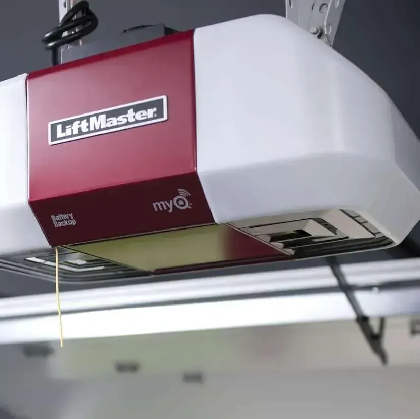 A red and white LiftMaster garage door opener mounted to a ceiling with a hanging manual release cord.