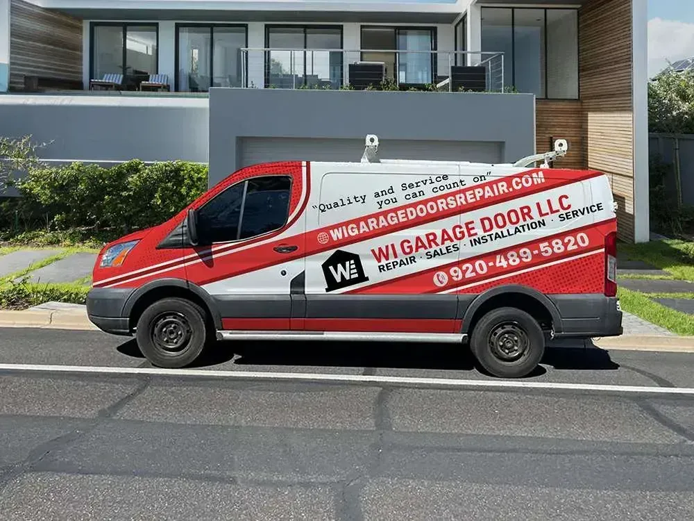 A red and white WI Garage Door LLC service van parked in a driveway in front of a modern house.