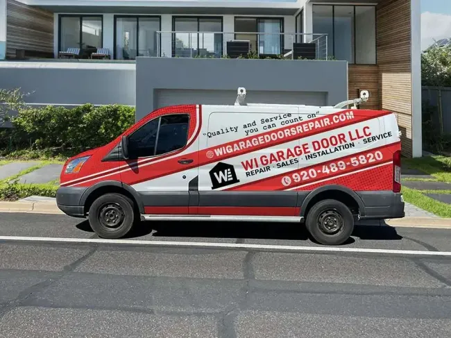 A red and white service van parked in front of a modern home, displaying