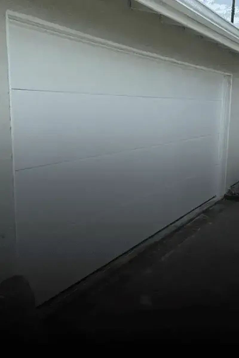A white, multi-panel garage door installed on the exterior of a building.