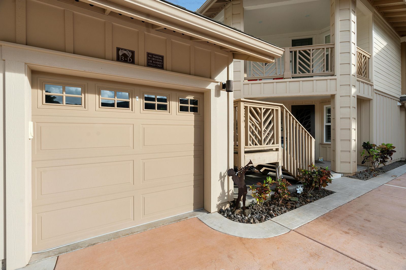 Beige garage door beside a small landscaped entry courtyard and stairway in an apartment complex