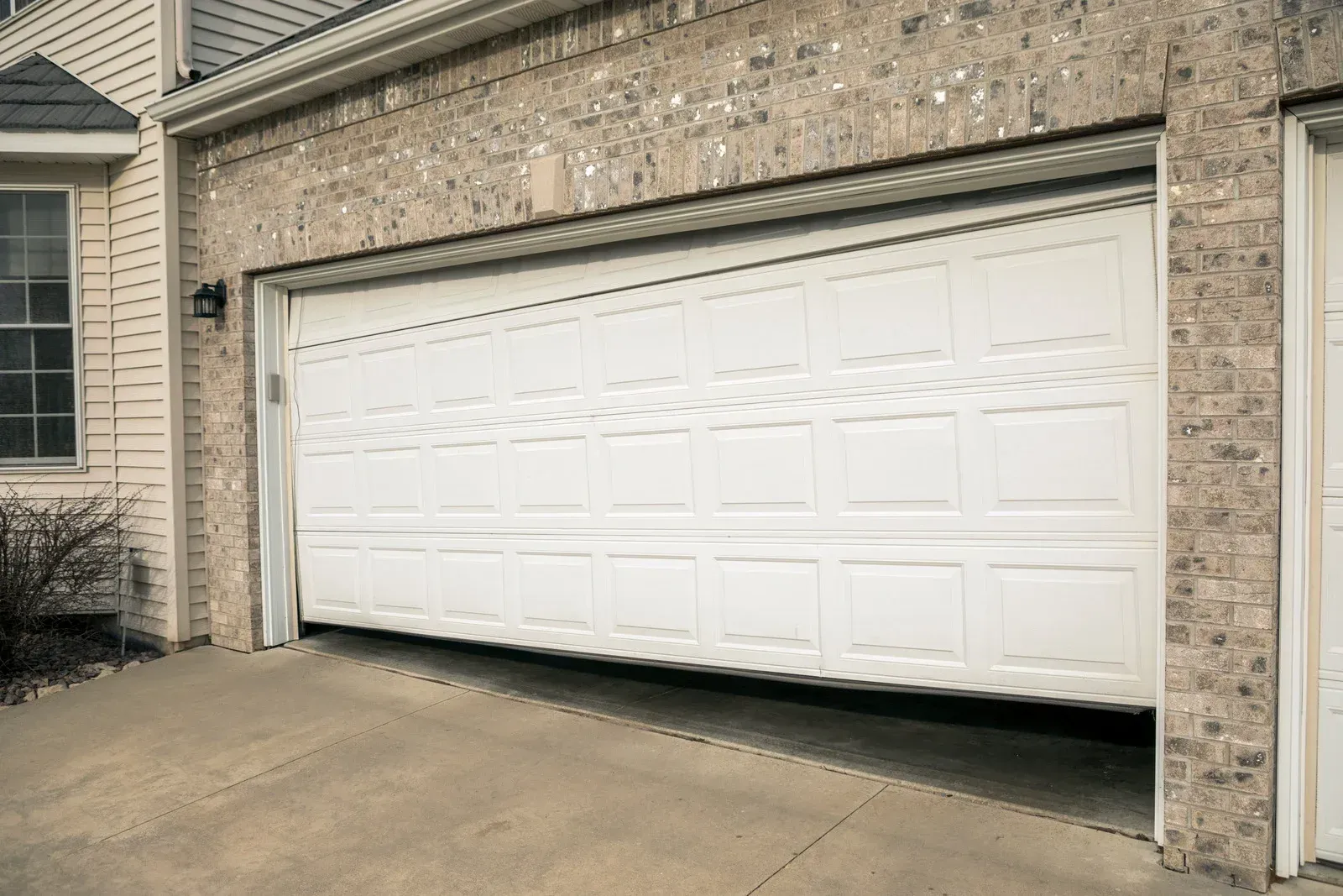 White garage door on a brick house driveway