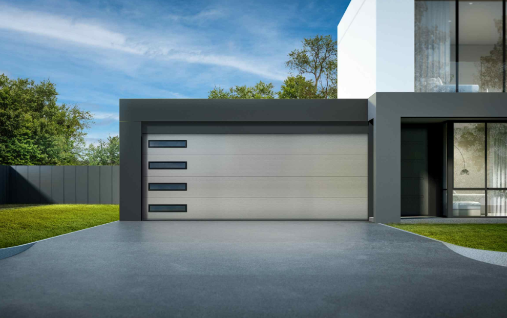 Modern house exterior with a large gray garage door and driveway under a blue sky