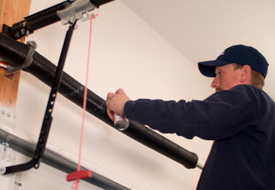 Worker adjusting a garage door opener rail with a red string guide