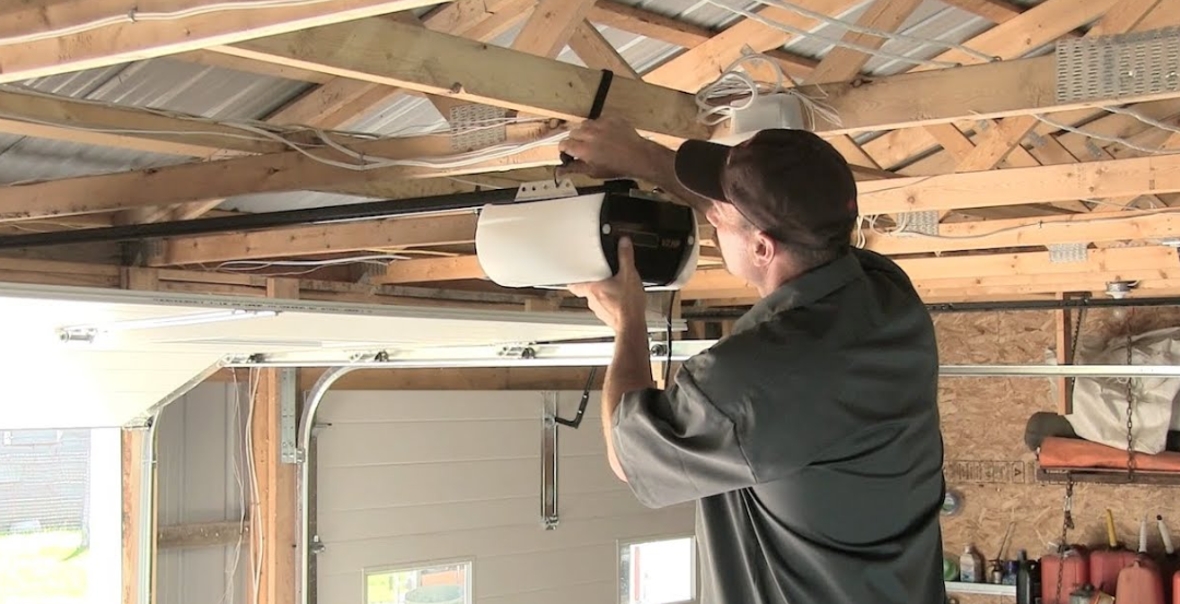 Person using a power drill to install a light fixture in an unfinished attic ceiling