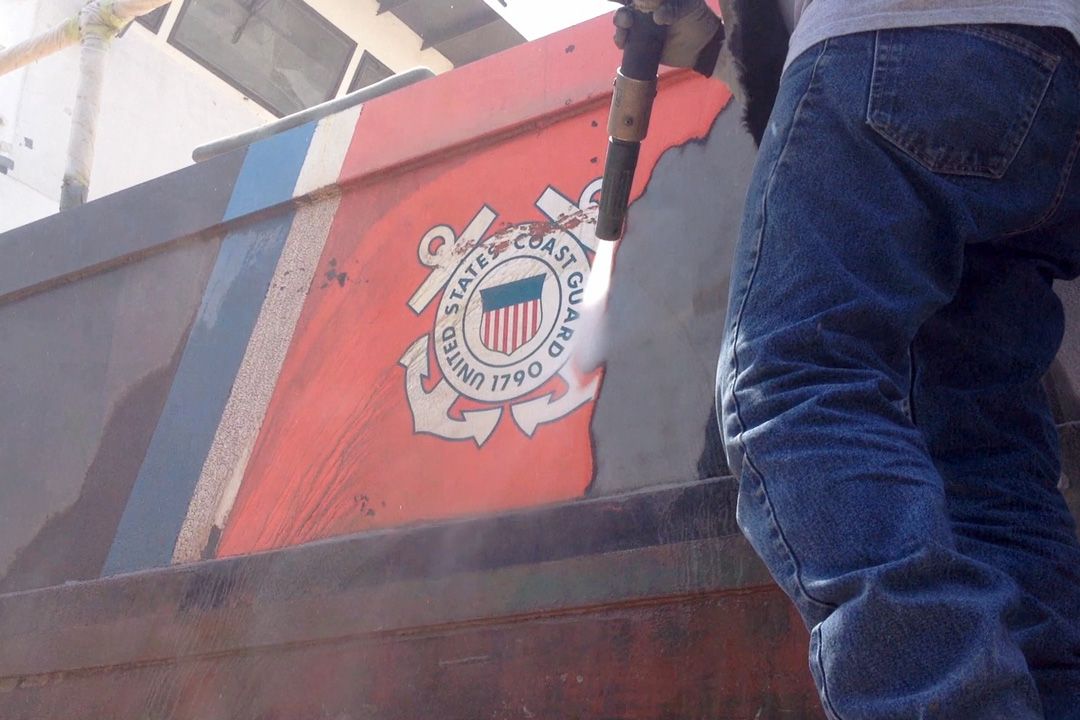 A person is standing in front of a boat that says united states coast guard