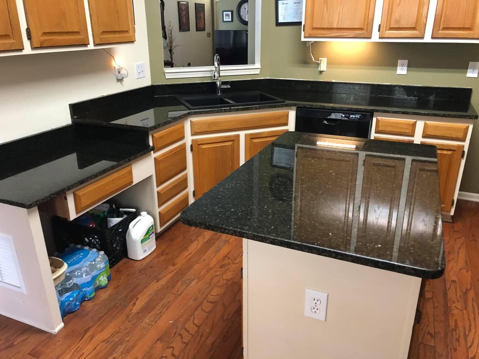 Kitchen with wood cabinets, black countertops, and an island with dark speckled granite.