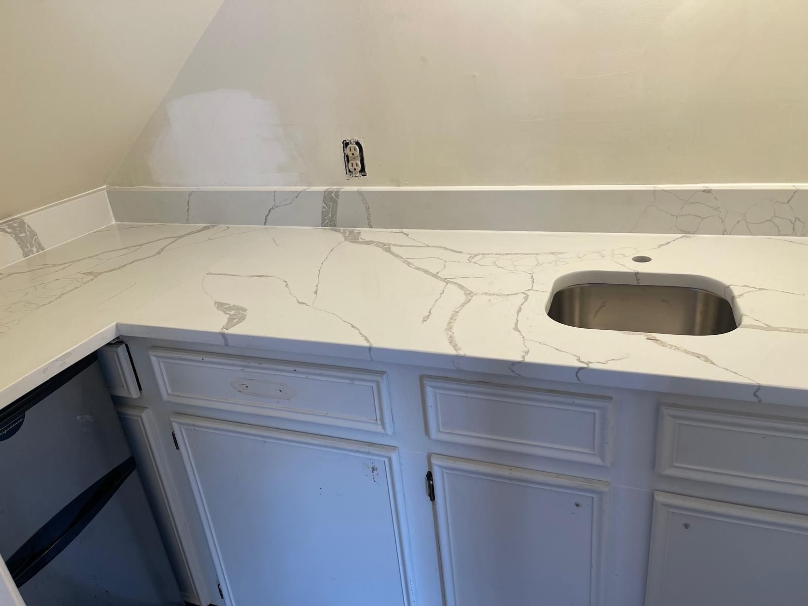 White quartz countertop with a sink over white cabinets.