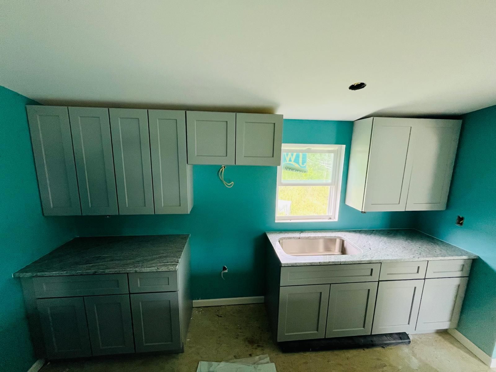 Kitchen with gray cabinets, teal walls, and granite countertops.