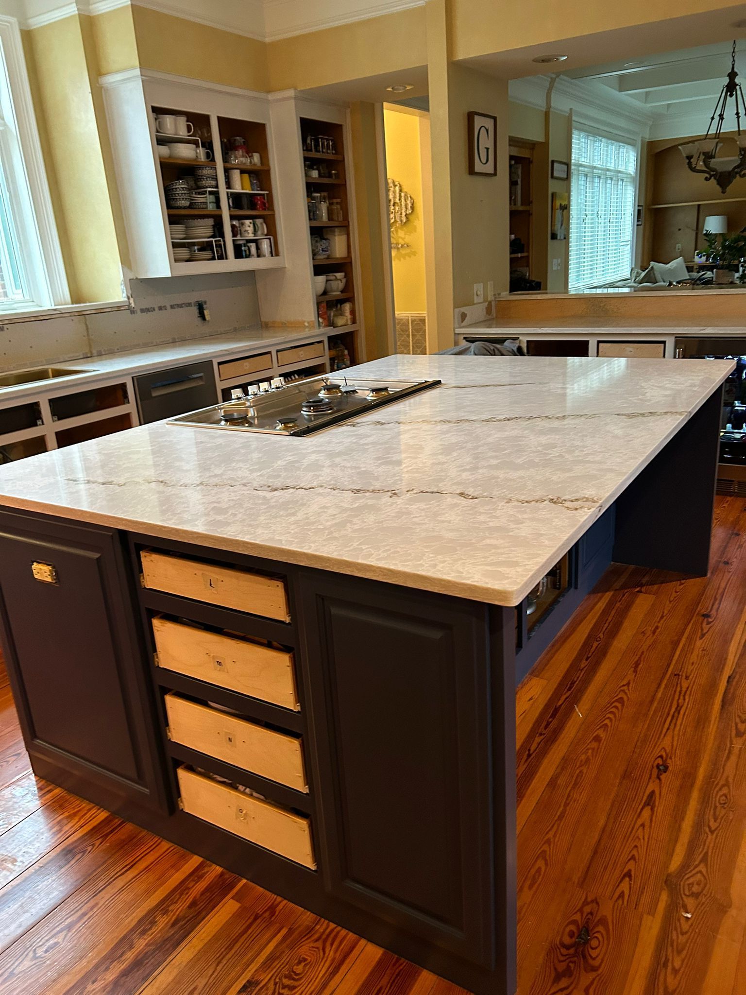 Kitchen island with dark blue cabinets, light countertops, and wood floors.