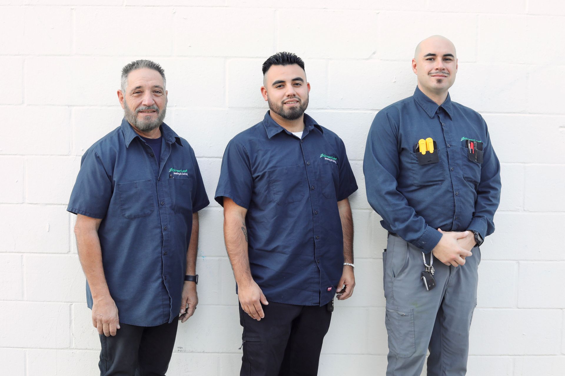 Three men are posing for a picture in front of a tree.