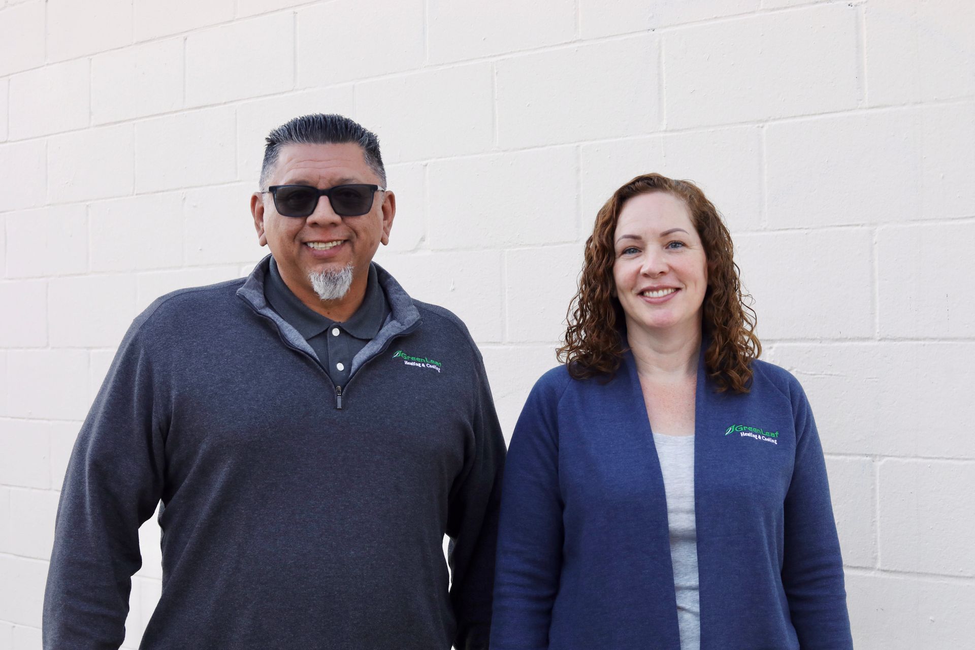 A man and a woman are posing for a picture in front of a tree.