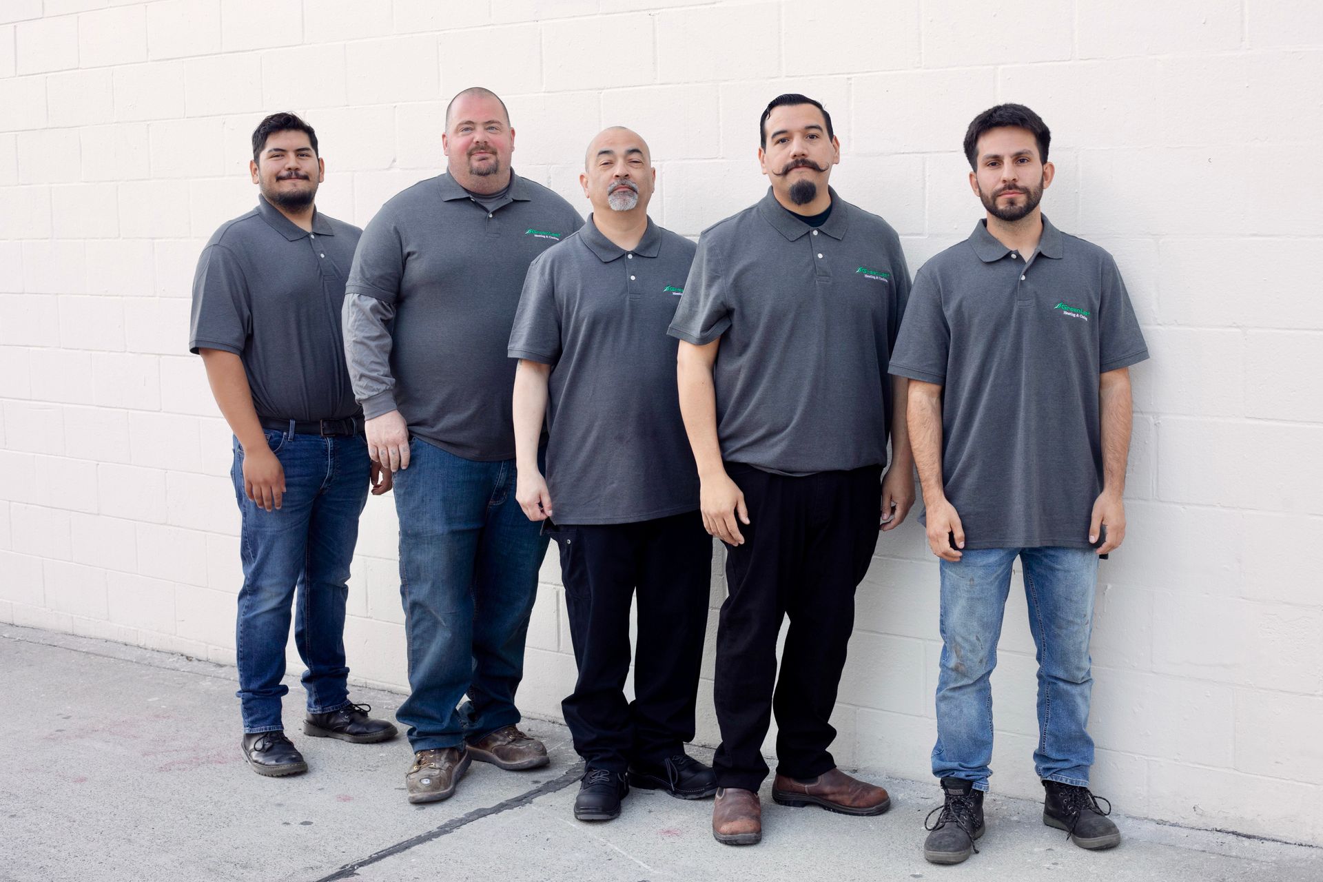 Three men are standing next to each other with their arms crossed in front of a tree.