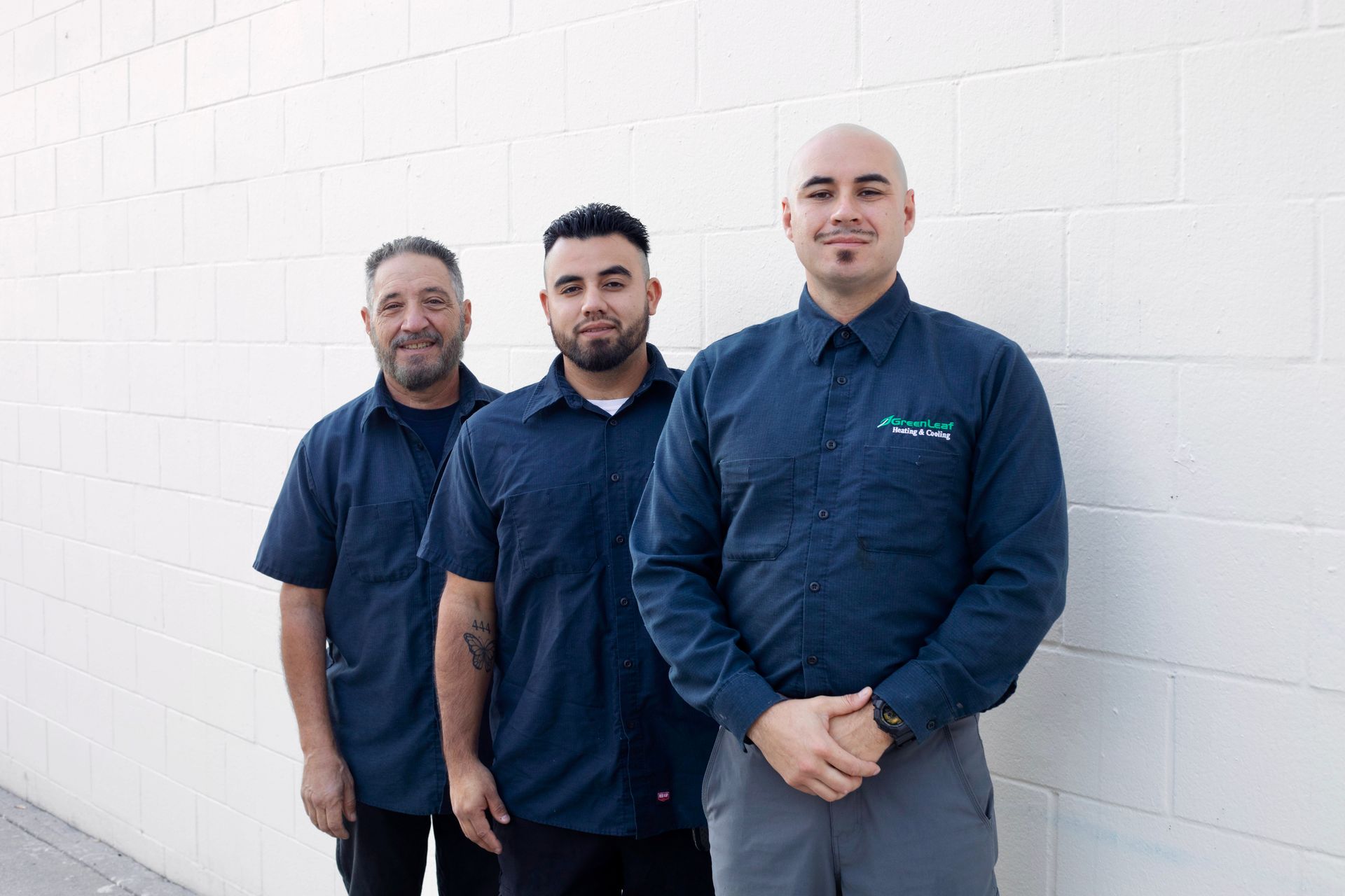 Three men are posing for a picture in front of a tree.