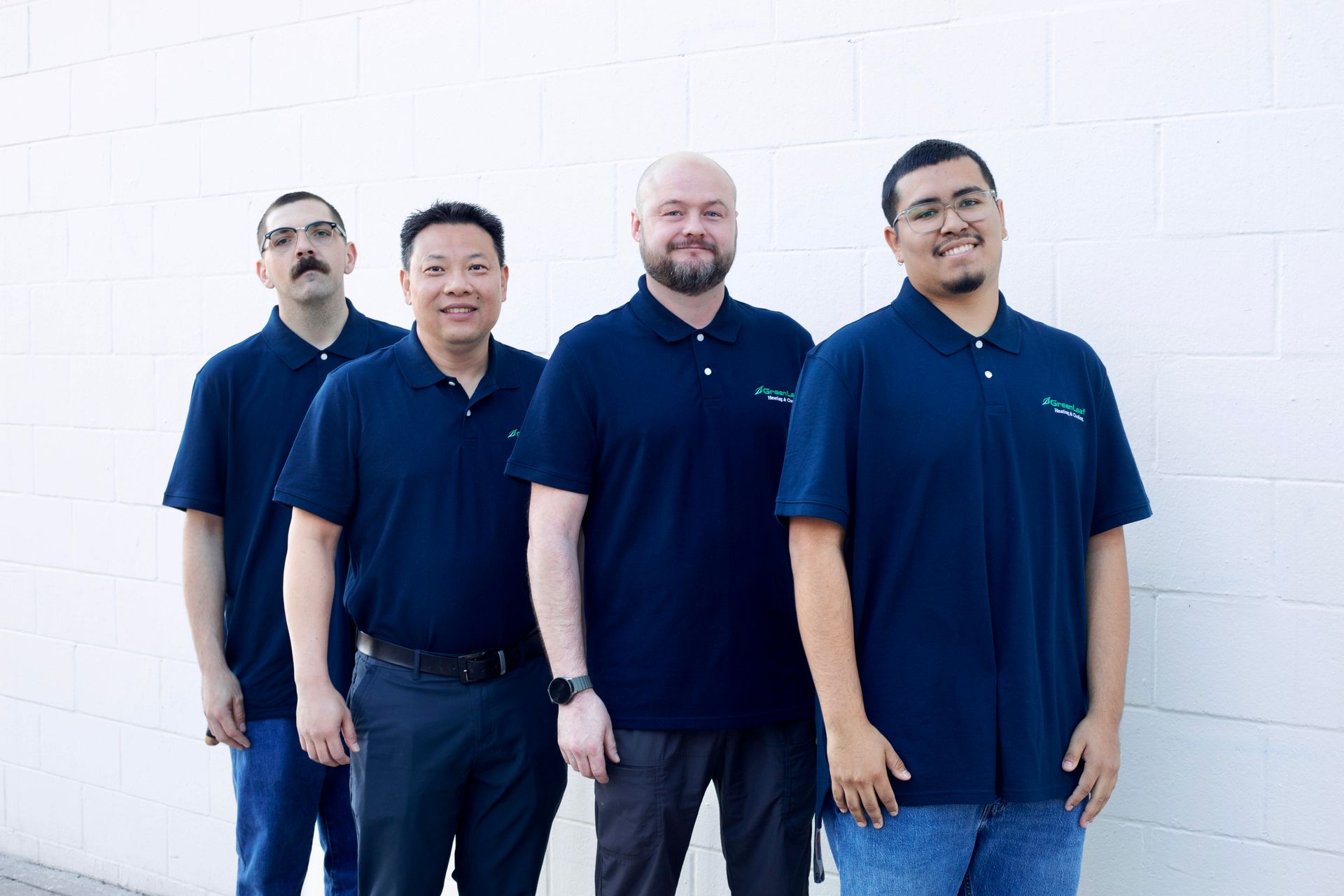 Three men are standing next to each other in front of a tree in a park.