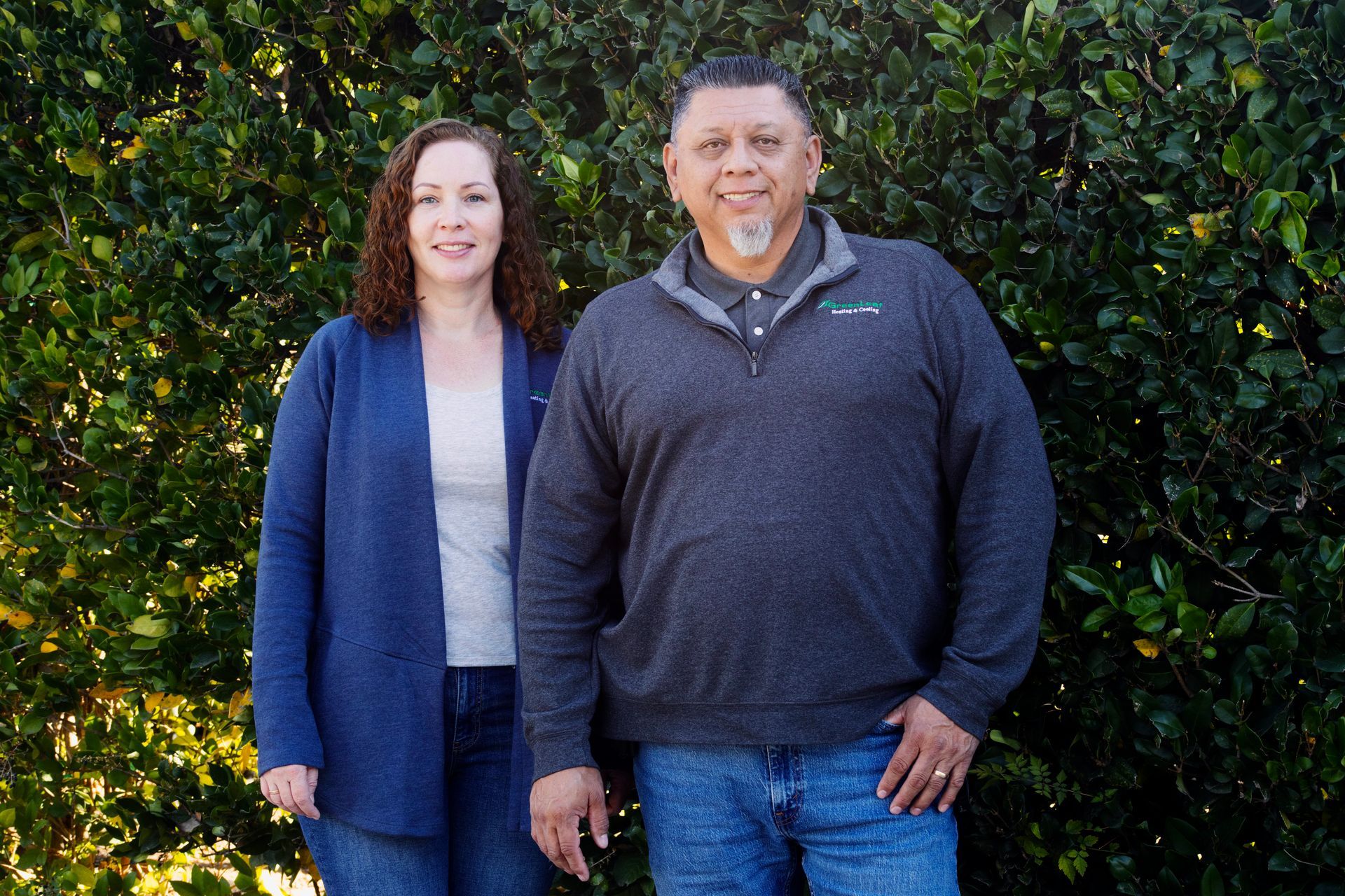 A man and a woman are posing for a picture in front of a tree.