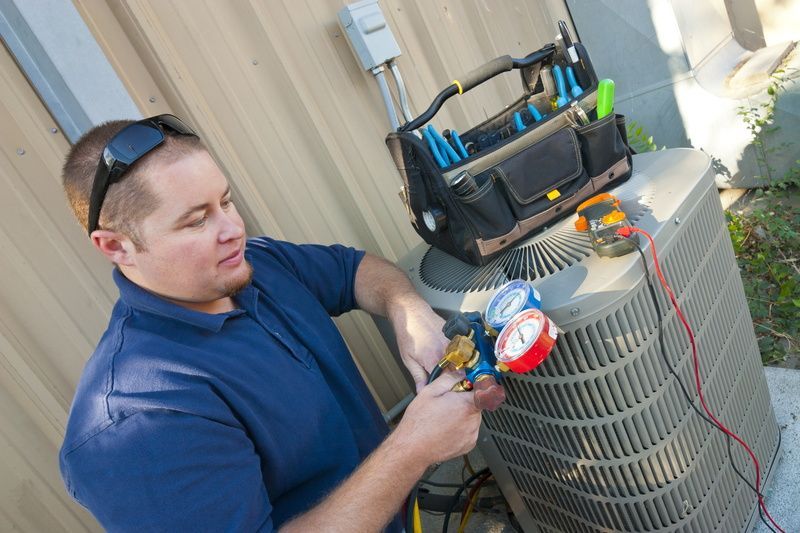 A man is working on an air conditioner outside of a building.