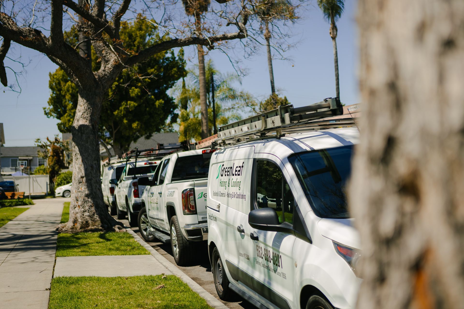 A row of white vans are parked on the side of the road.