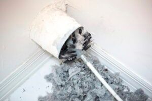 A vacuum cleaner is being used to clean a dryer vent.