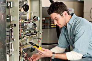 A man is working on an air conditioner with a multimeter.