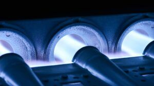 A close up of a gas burner with blue flames coming out of it.