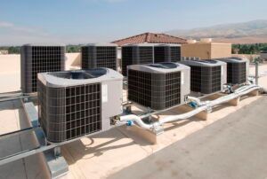 There are a lot of air conditioners on the roof of a building.