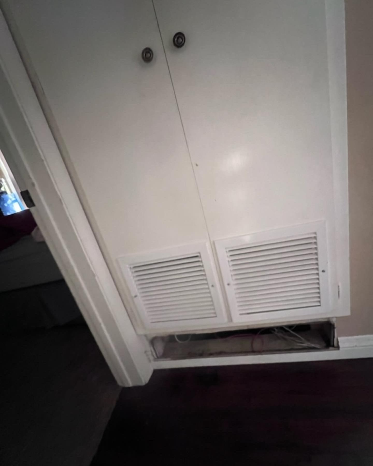A white cabinet with a vent on the ceiling in a room.