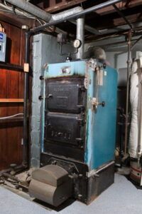 A blue and black boiler is sitting in a basement