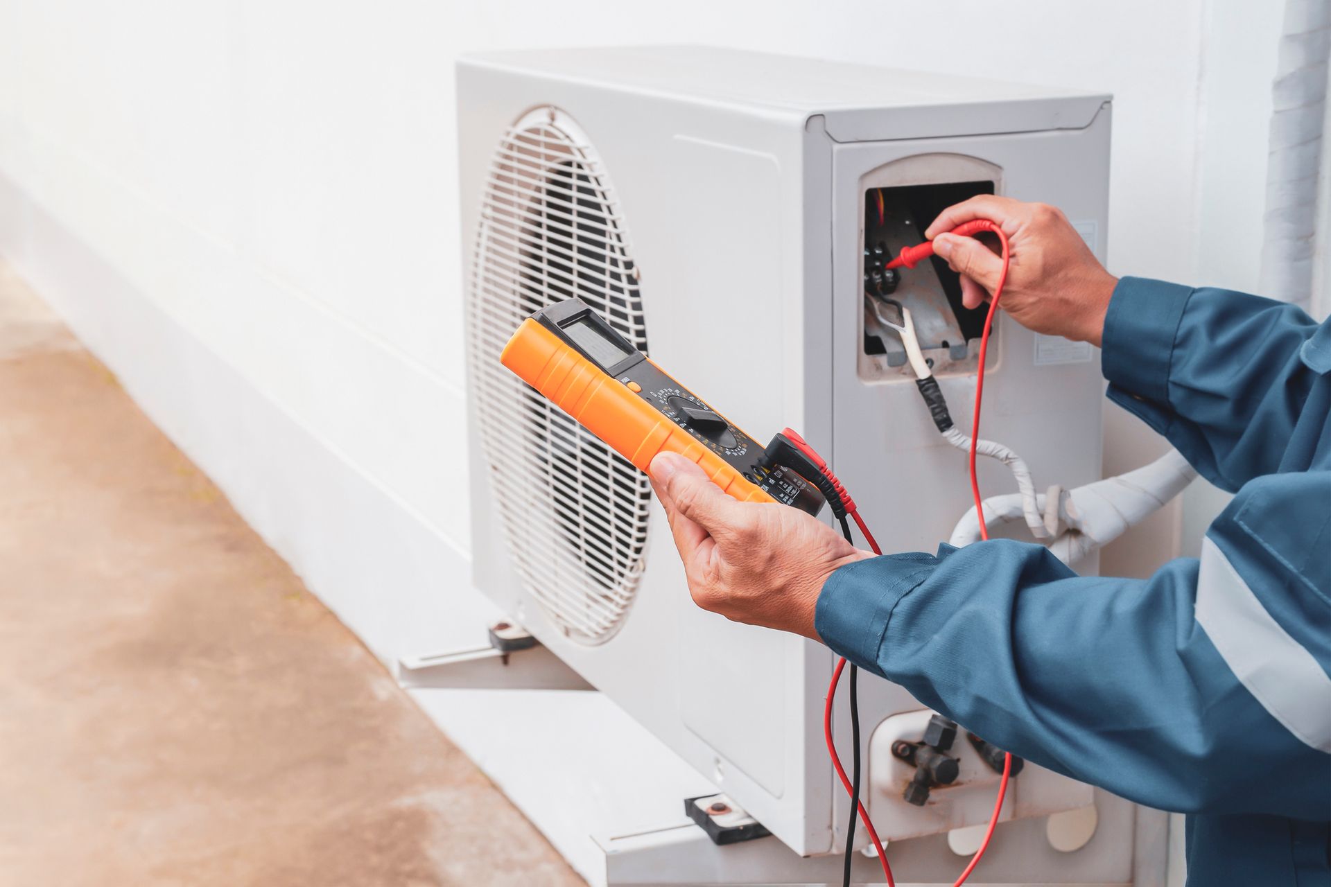 HVAC technician repairing central air conditioning outdoor unit during spring AC maintenance.