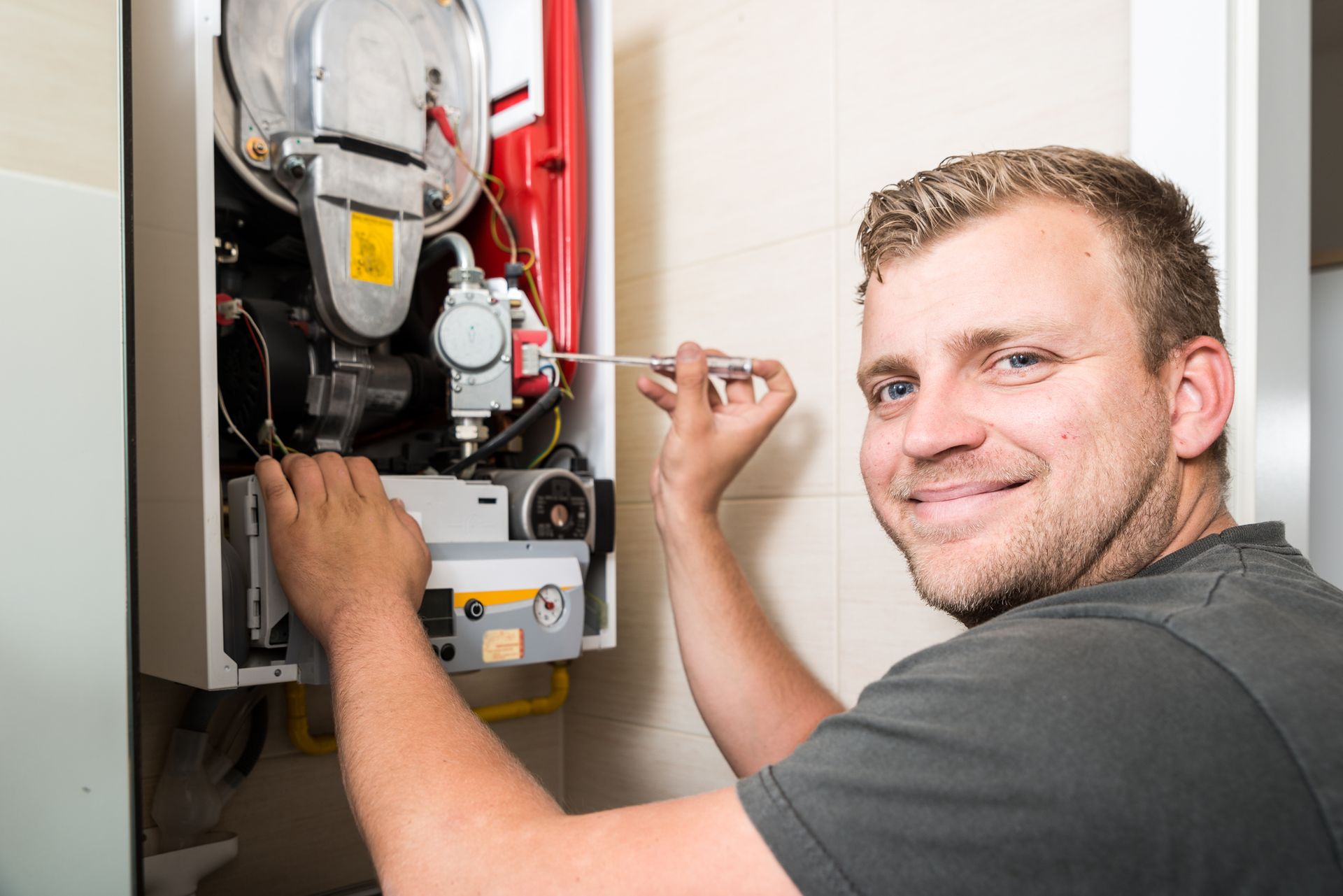 A professional technician performing heating system maintenance on an HVAC unit in a Southern Califo