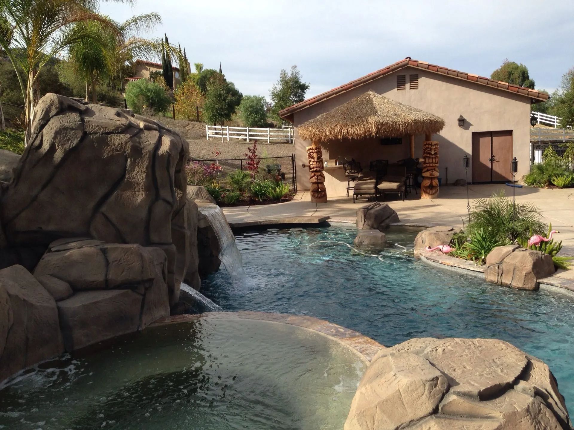 Pool with rock features, waterfall, and thatched roof structure.