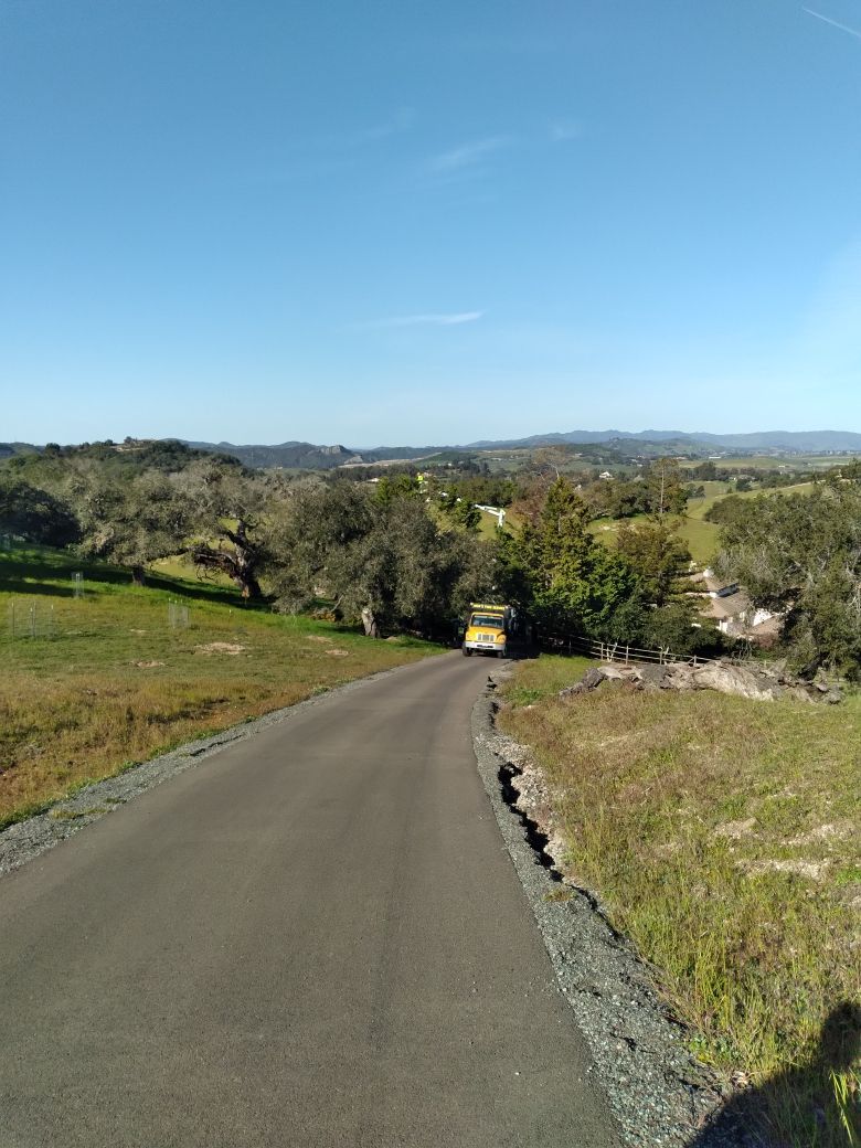 A car is driving down a road in the countryside.