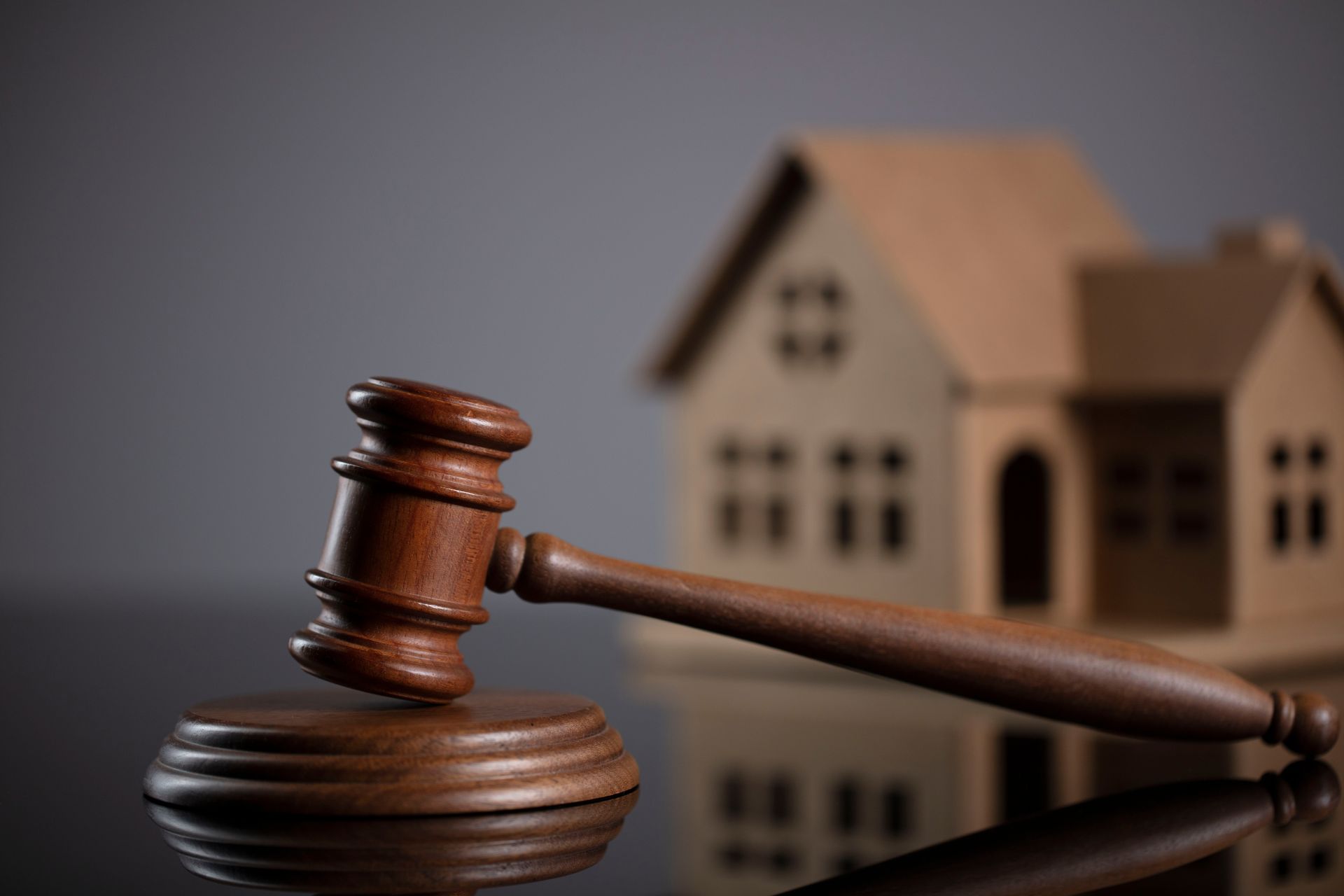 Wooden gavel and block in front of a miniature house, foreclosure in Montgomery, Alabama