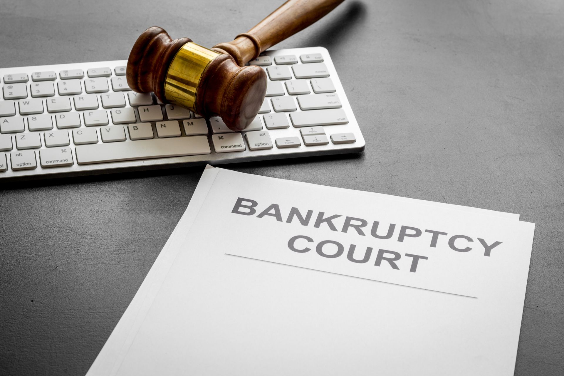 Gavel on keyboard next to bankruptcy court document on a desk.