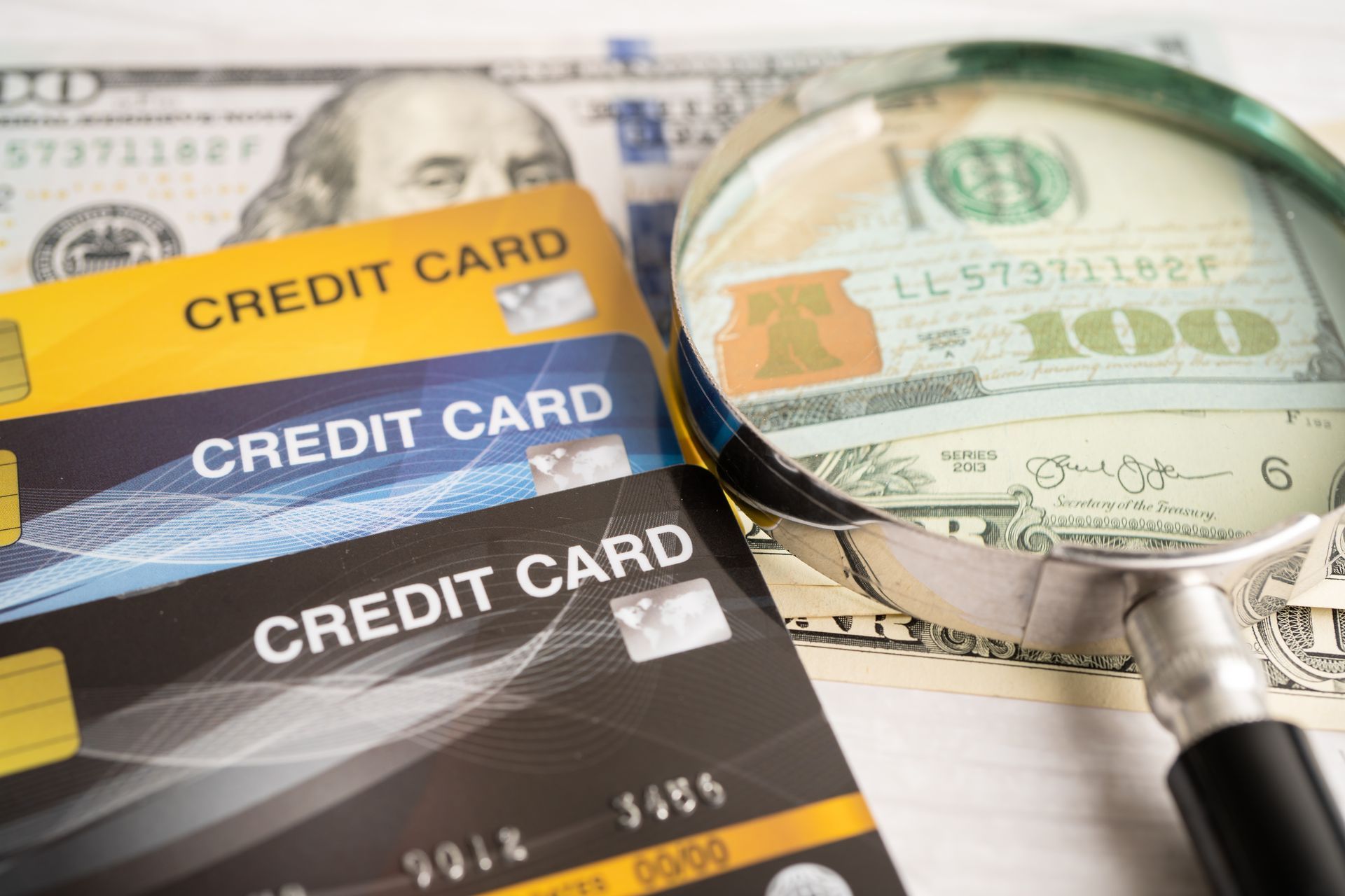 Credit cards and cash under a magnifying glass, possibly investigating finances.