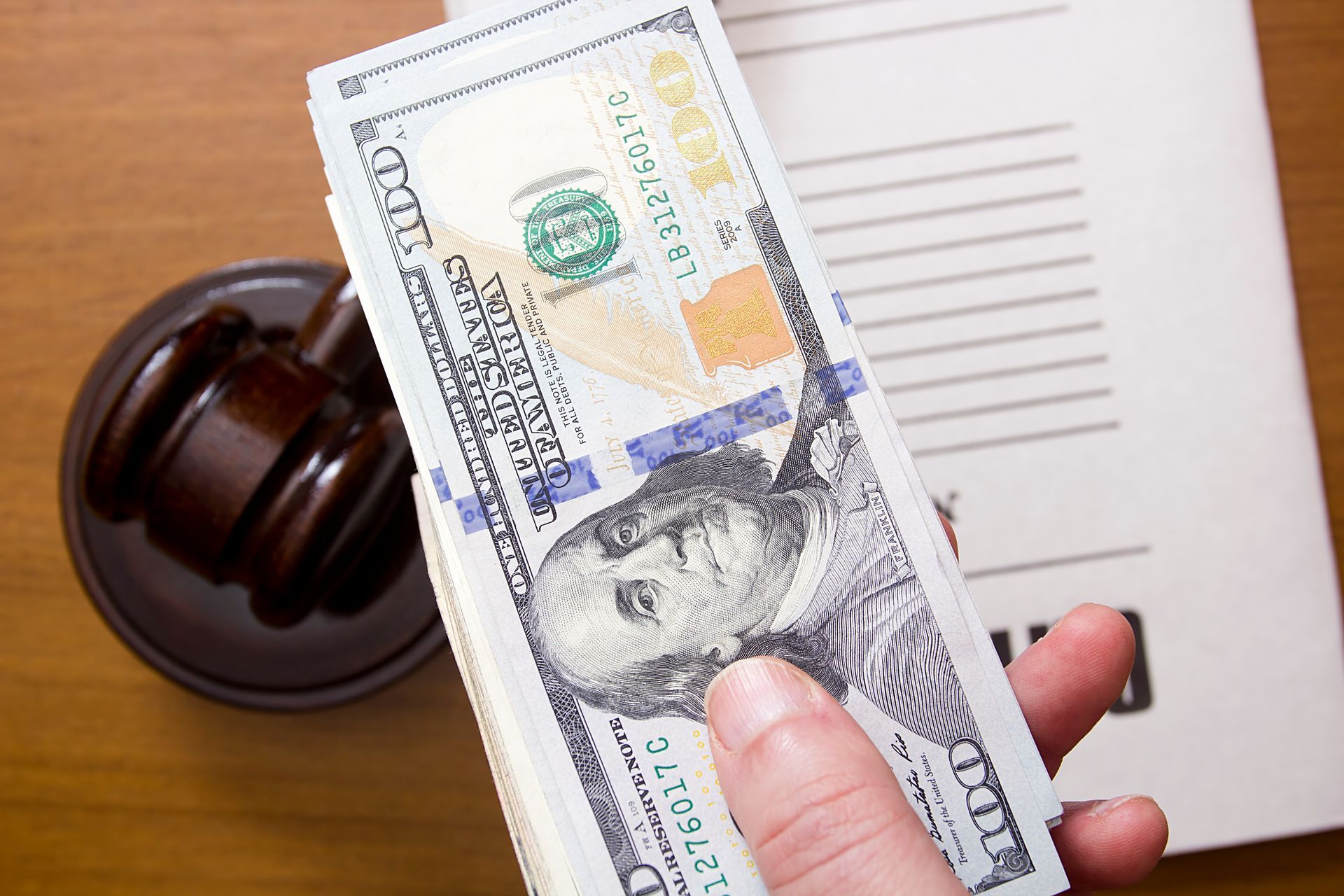Hand holding a stack of $100 bills, representing wage garnishments in Montgomery, Alabama.