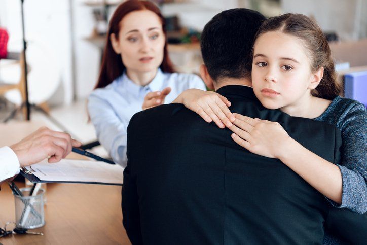 Girl hugs man in suit sitting opposite woman