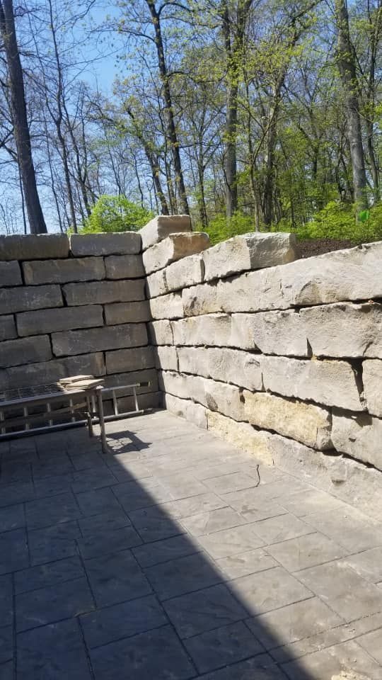 Stone retaining wall bordering a paved patio.