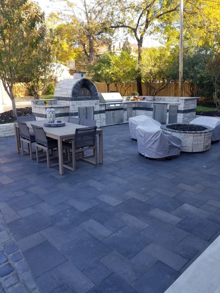 Outdoor patio with a stone oven, grill, seating area, and a dark blue brick patio.