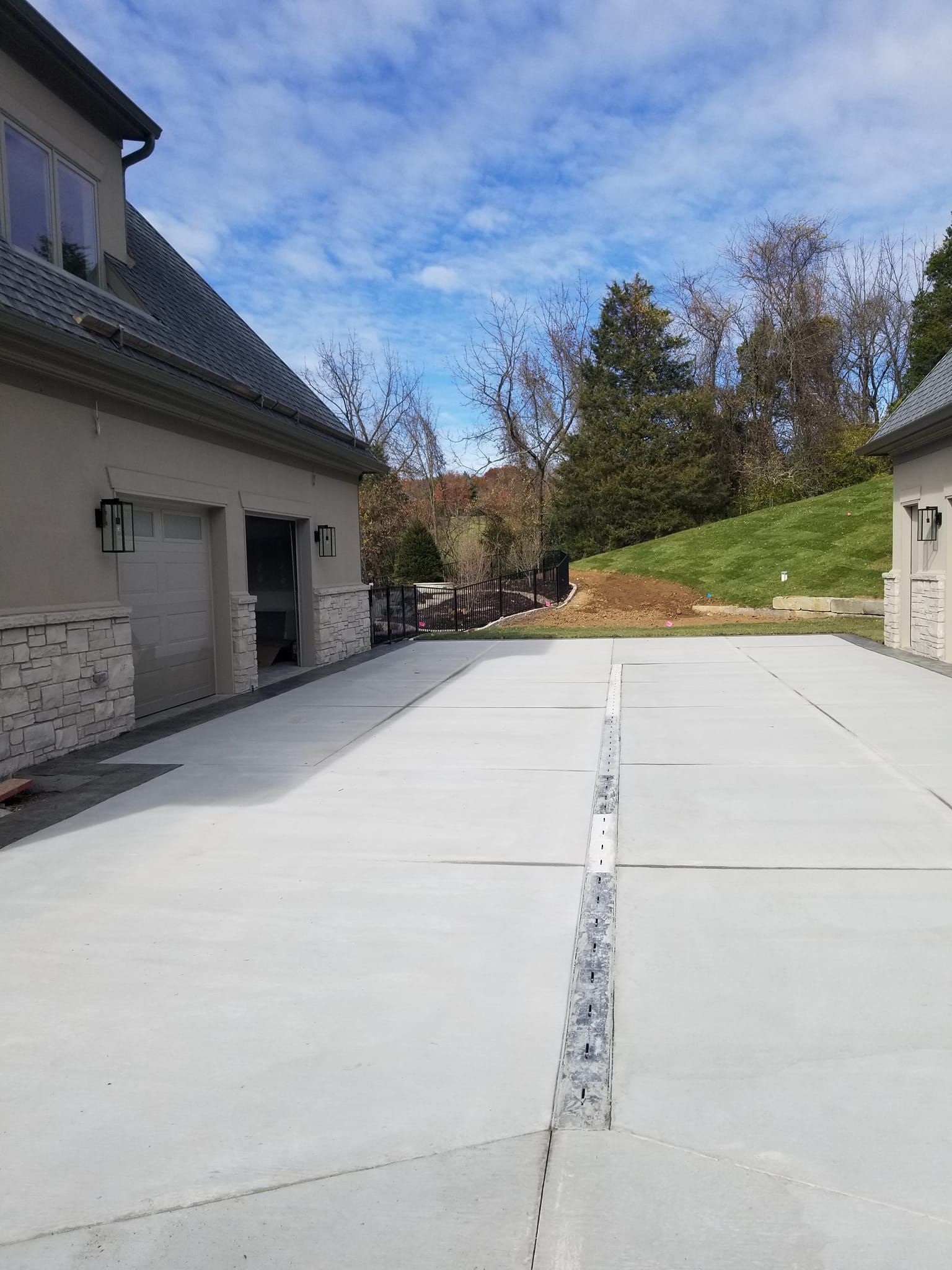 Driveway between two buildings with a central drainage channel; blue sky with some clouds in the background.
