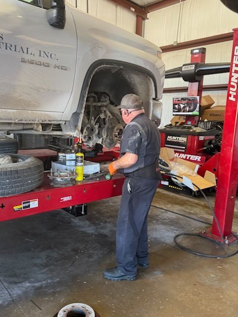 Mechanic working on a truck on a lift in a shop, using a torch.
