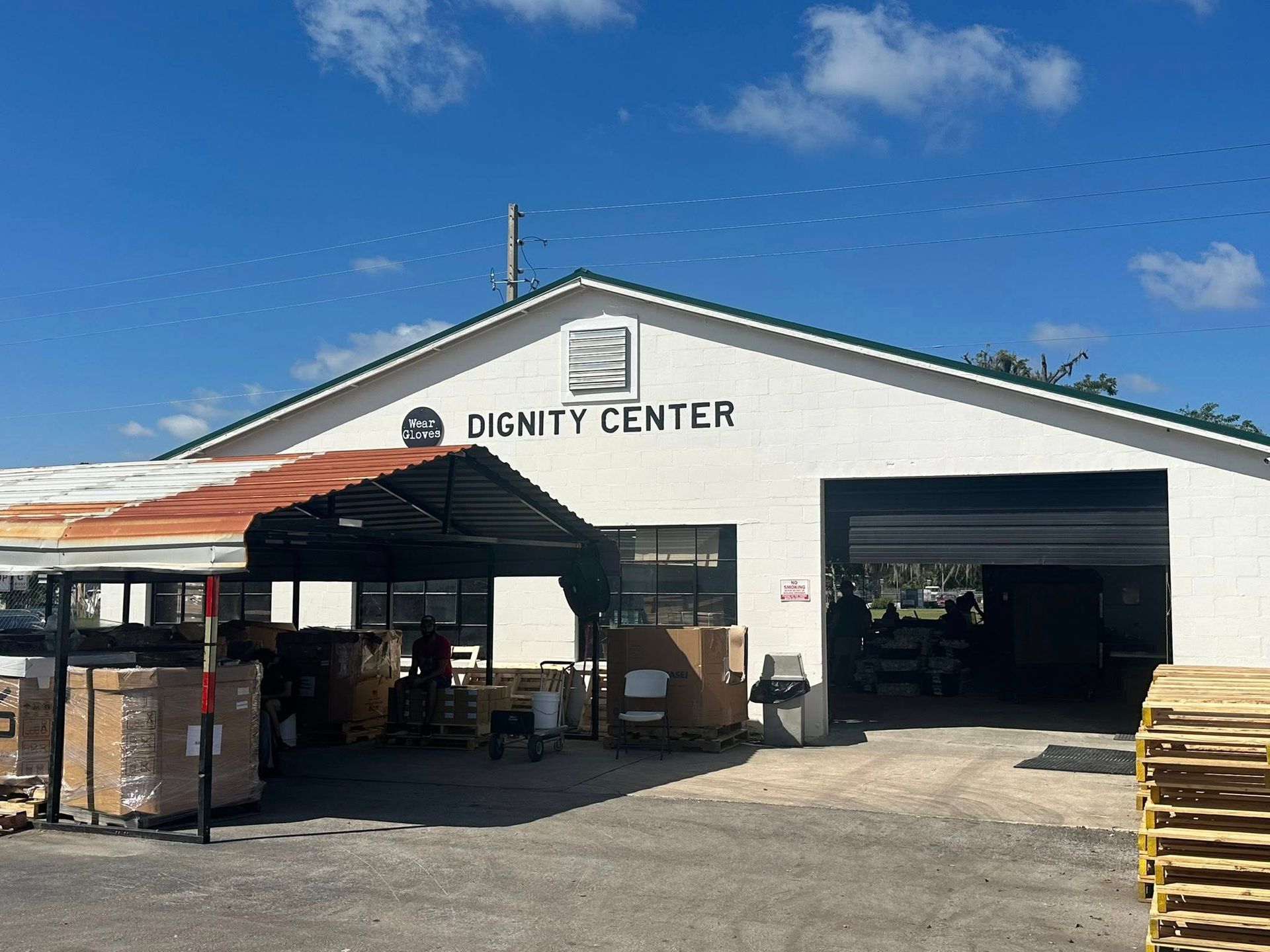 Exterior of the Dignity Center, a white building with an open garage door and a covered loading area.