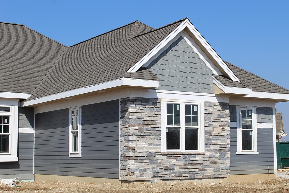 A house under construction with a gray siding and stone facade